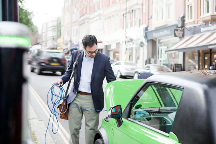 Man charging electric car on the street